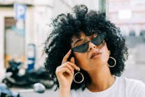 Pretty ethnic woman in white t-shirt and with black curly hair over black glasses — Stock Photo
