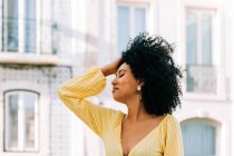 Гарненька етнічна жінка з чорним кучерявим волоссям дивиться на вулицю — стокове фото