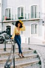 Mulher afro-americana na moda em top de cultura e jeans apoiados em trilhos e sorrisos — Fotografia de Stock