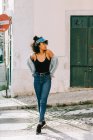 Junge afrikanisch-amerikanische Frau in Jeans und schwarzem Tank-Top steht tagsüber auf der Straße der Stadt — Stockfoto