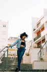 Fashionable African American woman in crop top and jeans walking downstairs — Stock Photo