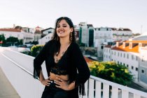 Schöne stilvolle Frau im schwarzen Outfit steht an einem sonnigen Tag an einer Brücke mit Stadtlandschaft in Lissabon — Stockfoto