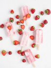 D'en haut popsicles roses et fraises fraîches mûres sur fond blanc — Photo de stock
