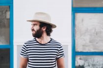 Young male in hat and striped t-shirt looking away — Stock Photo