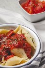 Вкусная паста с базиликом и красным томатным соусом подается на белой тарелке — стоковое фото
