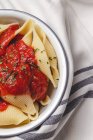 Köstliche Conchiglie-Pasta mit Basilikum und roter Tomatensauce auf weißem Teller — Stockfoto