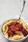 Deliciosa pasta conchiglie espolvoreada con albahaca y salsa de tomate rojo servido en plato blanco - foto de stock
