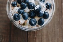 Bowl of summer dessert topped with blueberries and chia seeds on wooden table — Stock Photo