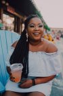 Afrikanisch-amerikanische junge Frau trinkt kalte Getränke, während sie im Hipster-Café sitzt und wegschaut — Stockfoto