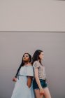 Multiracial young casual women laughing and hugging while standing on street wall — Stock Photo
