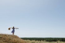 Visão traseira da mulher adulta em chapéu de palha e vestido com câmera em pé na colina — Fotografia de Stock