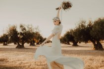 Zufriedene Frau im Kleid mit offenem Rücken, erhobene Hände mit Blumenstrauß — Stockfoto