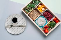 Caja de alimentos con ingredientes dietéticos por libro de texto y plato - foto de stock