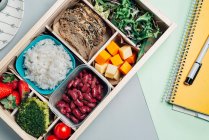 Caja de alimentos con ingredientes dietéticos por libro de texto y plato - foto de stock