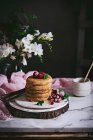 Stack of raspberry pancakes with fresh berries on porcelain plate over dark background — Stock Photo