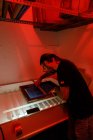 Konzentrierte männliche Künstler mit langen Föhnen Druck Siebdruck rot beleuchteten Raum der Werkstatt — Stockfoto