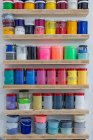Prateleiras com latas coloridas de tinta de diferentes tamanhos e cores no local de trabalho — Fotografia de Stock