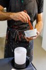 Hombre cultivador concentrado que lleva delantal sucio mezclando varias pinturas para serigrafía en taller. - foto de stock
