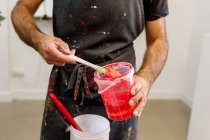 Концентрований врожай чоловік в брудному фартуху, що змішує різні фарби для серцебиття в майстерні — стокове фото