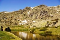Pequeno lago no fundo da montanha rochosa com neve na Serra de Guadarrama Espanha — Fotografia de Stock