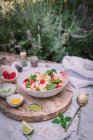 Сверху аппетитный салат и ягоды соуса нарезанные известью на деревянном стенде с солью и перцем на столе — стоковое фото