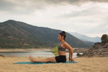 Mulher adulta média fazendo ioga ao ar livre na praia da barragem — Fotografia de Stock