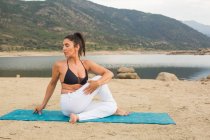Середня доросла жінка робить йогу на відкритому повітрі на пляжі греблі — стокове фото