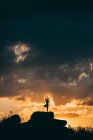 Silhouette of woman doing yoga tree pose outdoors at sunset — Stock Photo