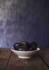 Ceramic bowl of ripe healthy figs on aged wooden table against blue wall — Stock Photo