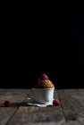 Ceramic cup with yummy raspberry muffin placed on shabby timber tabletop against black background — Stock Photo
