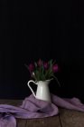 Winziger Metalleimer mit leuchtend violetten Blüten auf einer Holztischplatte — Stockfoto