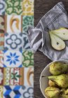 Tigela de peras frescas e frutas cortadas pela metade na mesa de madeira com guardanapo — Fotografia de Stock
