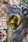 Bol de poires mûres sur surface nouée ornementale avec chiffon — Photo de stock