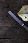 Knife and halved fresh ripe pear on wooden tabletop — Stock Photo
