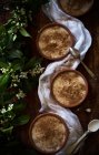 From above green blooming twigs placed near bowls with delicious fresh porridge and napkin on wooden tabletop — Stock Photo