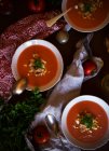 D'en haut bols de soupe de tomates délicieux avec du persil placé près des serviettes sur la table — Photo de stock