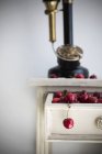 Bando de cerejas maduras frescas na gaveta do armário vintage contra a parede branca — Fotografia de Stock