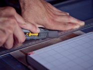 Безликий человек работает в букмекерской мастерской и измеряет обложку книги карандашом и линейкой — стоковое фото