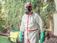 Fumigador em máscara respiratória e uniforme branco para fumigação pronto para plantas de desinfecção no quintal — Fotografia de Stock
