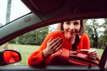 Femme mettant valise dans la fenêtre avant de la voiture — Photo de stock
