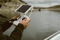 Hands of tourist using controller with tablet on stand while sailing on boat in water in cloudy day — Stock Photo