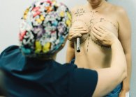 Rückenansicht einer Ärztin zeichnet Markierungen am Körper einer nackten Frau für Brustoperationen in der Klinik — Stockfoto
