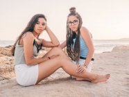 Усміхнені модні молоді жінки розслабляються на березі моря — стокове фото