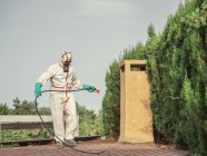 Specialist in uniform for fumigation holding hose analyzing distance for disinfection — Stock Photo