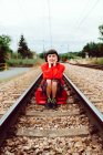 Femme assise sur des traverses au milieu du chemin de fer — Photo de stock