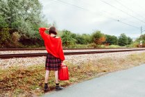 Woman looking at approaching modern train on railroad in countryside — Stock Photo