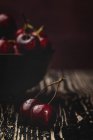 Вкусные спелые вишни на деревенском деревянном фоне с чашей — стоковое фото