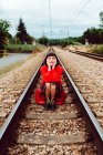 Femme assise sur des traverses au milieu du chemin de fer — Photo de stock