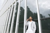 Elegante negro hablando de teléfono inteligente edificio inclinado - foto de stock