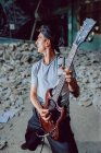 Un musicien joue de la guitare électrique dans un endroit abandonné — Photo de stock